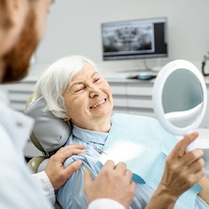 a patient checking her teeth with a mirror