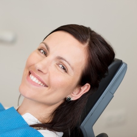 Smiling brunette woman leaning back in dental chair