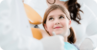 Young girl in dental chair looking up at her dentist