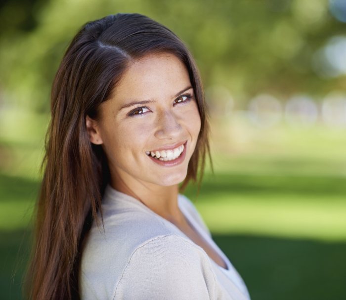 Woman with long brown hair smiling outdoors after cosmetic dentistry in Grenada