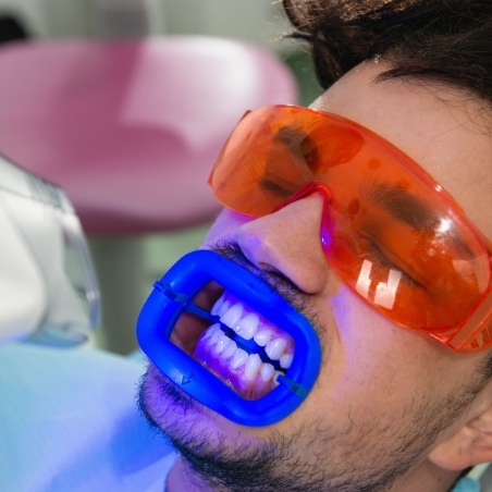 Man in dental chair receiving professional teeth whitening