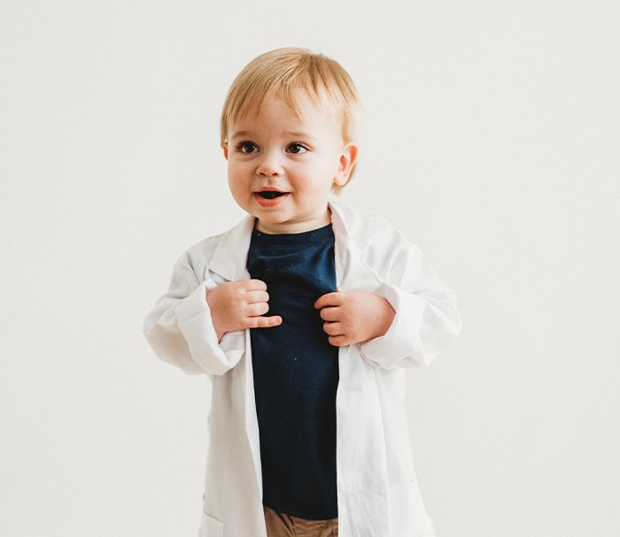 Smiling toddler wearing white lab coat