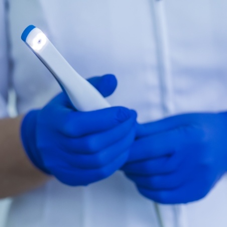 Dental team member holding white pen like intraoral camera