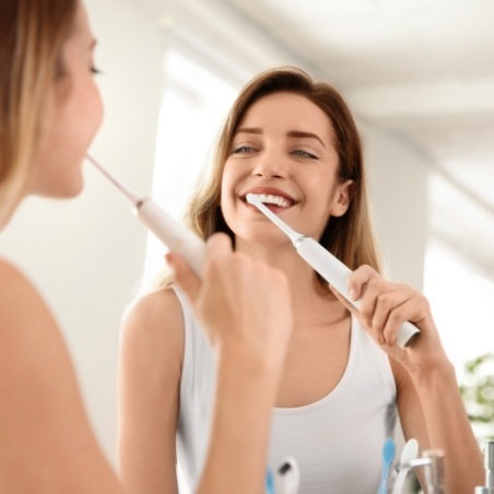 Woman smiling while brushing her teeth