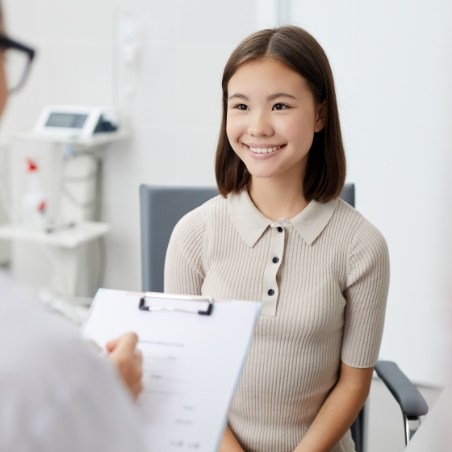 Woman smiling as her dentist writes on clipboard