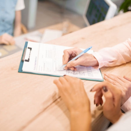 Dental team member showing a patient where to sign on a clipboard