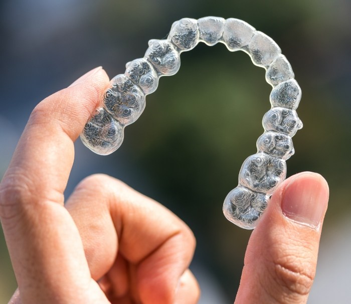 Close up of hand holding a Sure Smile clear aligner in Grenada