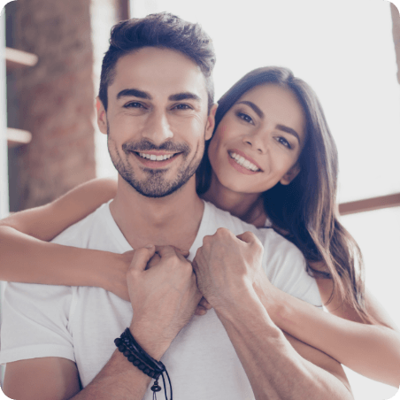 Young man and woman smiling and hugging at home