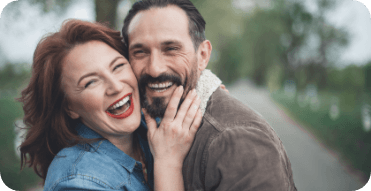 Smiling man and woman hugging outdoors