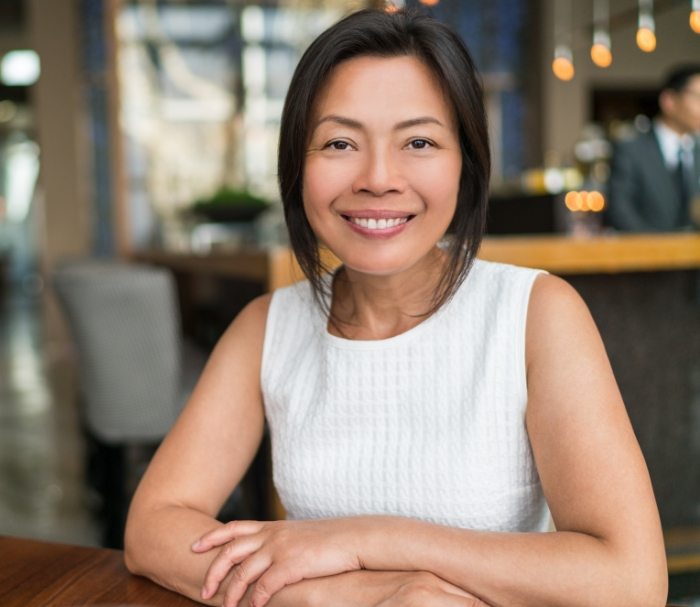 Woman at table in restaurant smiling after restorative dentistry in Grenada