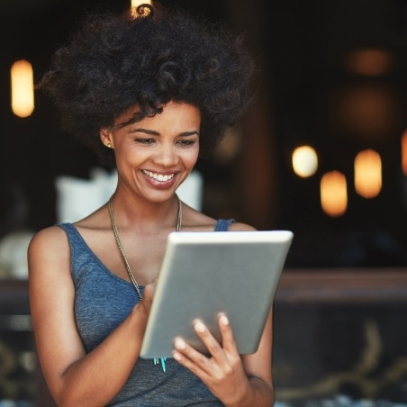 Woman smiling while looking at her tablet